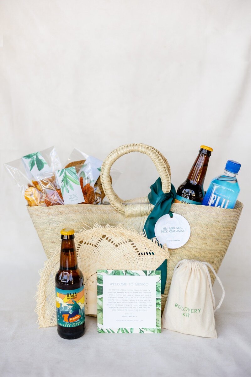 A large woven guest favor bag on behalf of newlywed couple, Mr. and Mrs. Nick Gialamas, filled with refreshments, an event schedule, a woven fan, and other items