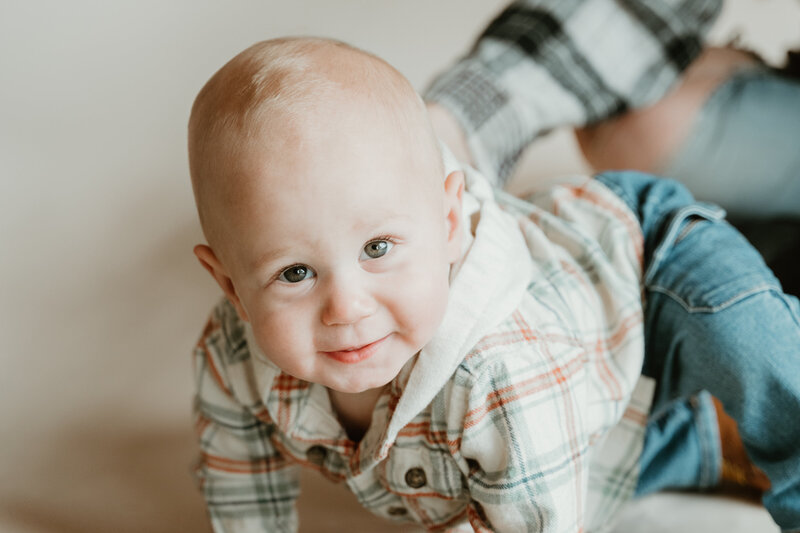 Image of a boy in a flannel and jeans crawling.