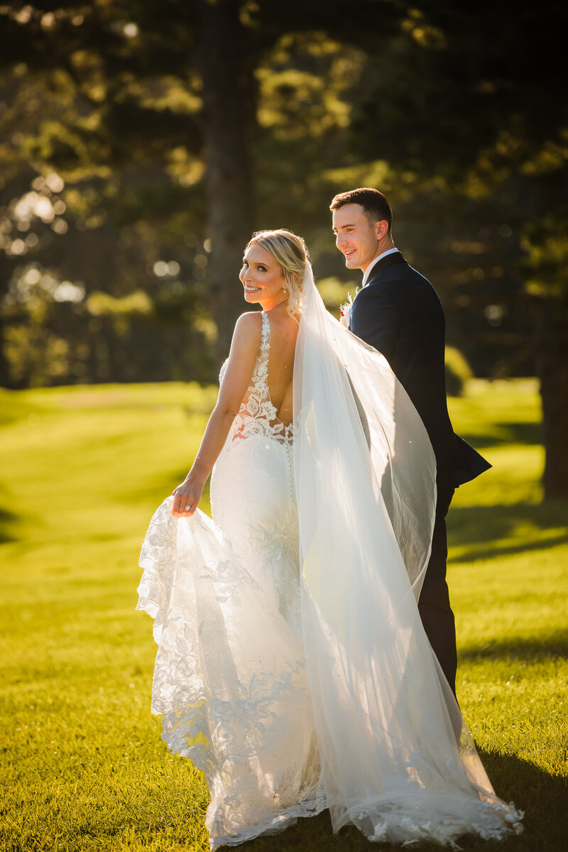 Couple in wedding attire is walking holding hands at sunset time at Springfield country club, Pennsylvania