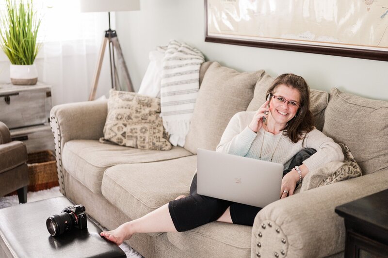 Lifestyle brand photograph of business owner  working simultaneously on her cell phone and laptop from her living room, a picture of entrepreneurship