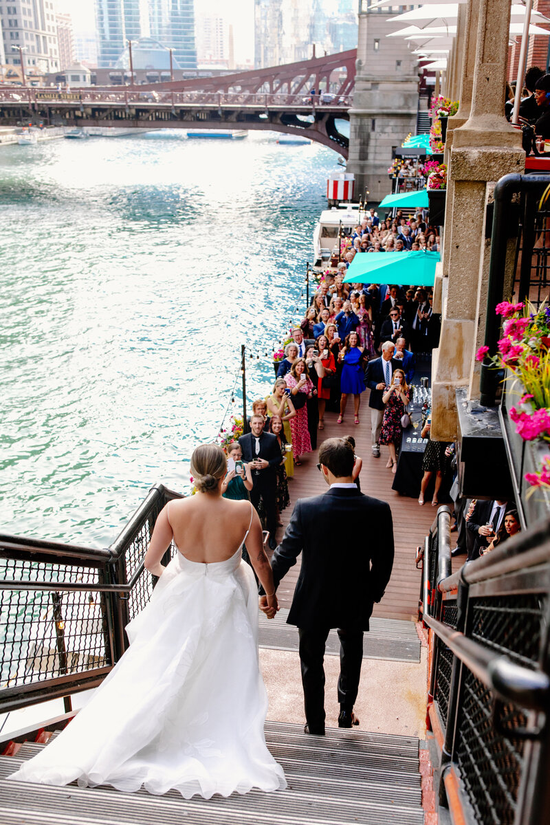 Bride and groom walk down stairs to the Chicago River