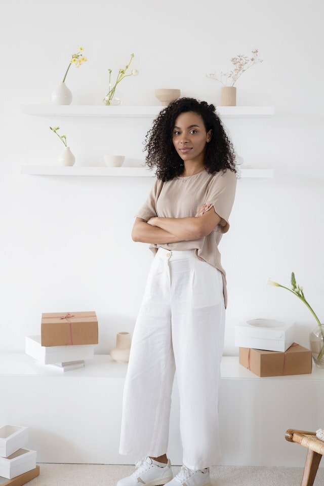 Young woman smiling and standing in her office with her arms crossed