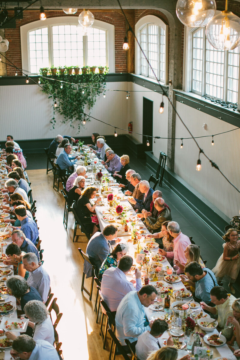 People sitting down, talking, and eating in a rectangular table at The Evergreen