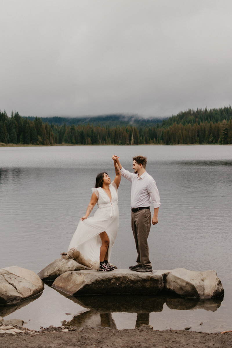 Bride and groom twirling on a rock at Trillium Lake in Mt. Hood National Forest in Oregon. 