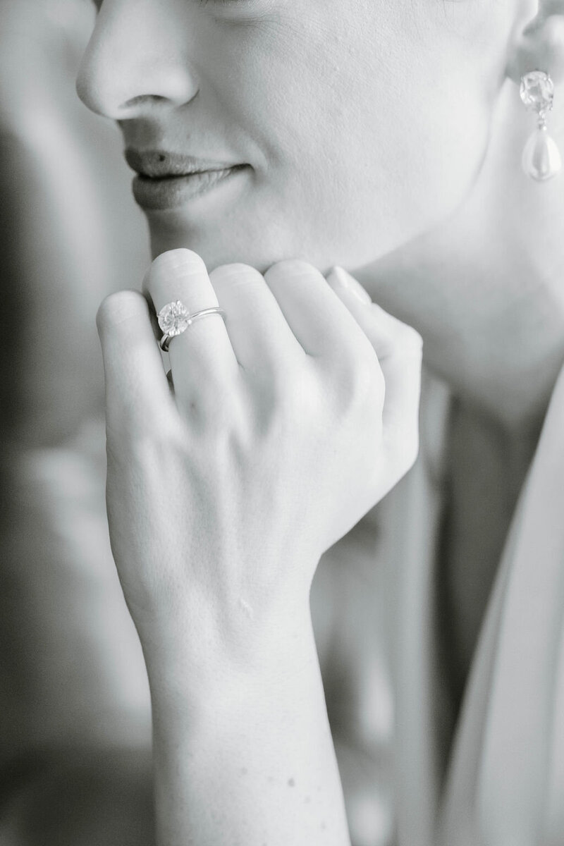 Wedding Photographer RI | A black-and-white close-up of a woman gazing softly, wearing a ring on her left hand and dangling earrings.