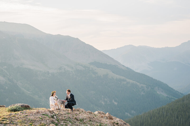 A couple embraces in front of alpine lake at sunrise in Colorado