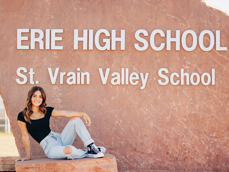 Girl sitting in front of Erie Highschool sign