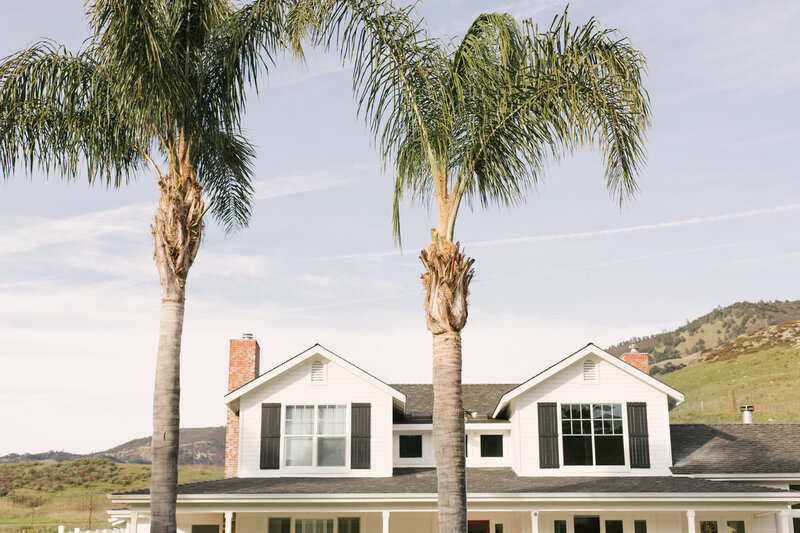 White two story home with palm trees in front yard