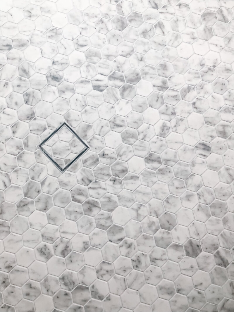 Hexagonal white and gray marble tiles with a single square tile outlined, showcasing the elegance typical of bespoke interior design in Newcastle.