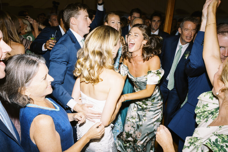 bride and groom stop mid-way down the flower-lined aisle to dip and kiss while guests smile and clap.
