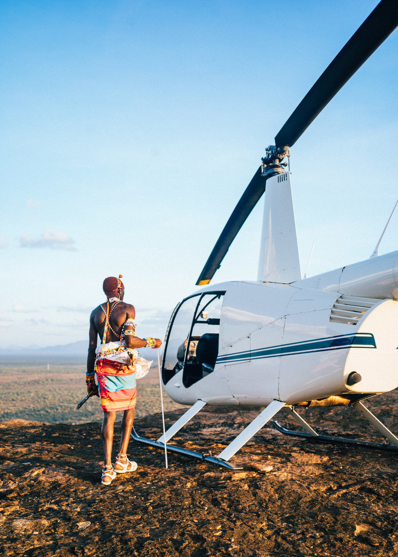 samburu warrior looking at helicopter in kenya