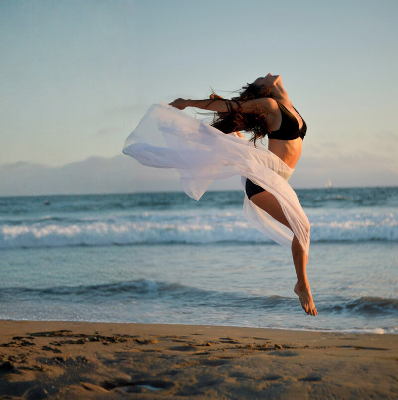 Frau bewegt sich frei am Strand bei Sonnenuntergang - Ausdruck von Körpergefühl, Leichtigkeit und Wohlbefinden