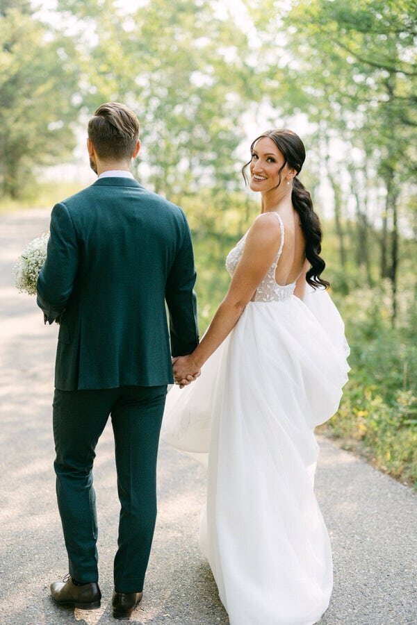 Captured during a summer day, this image shows the bride and groom walking hand in hand at the Nordic Spa in Kananaskis Country. Fresh from their first look, their joyful connection and the serene spa setting perfectly frame their first steps together as a soon-to-be-married couple.