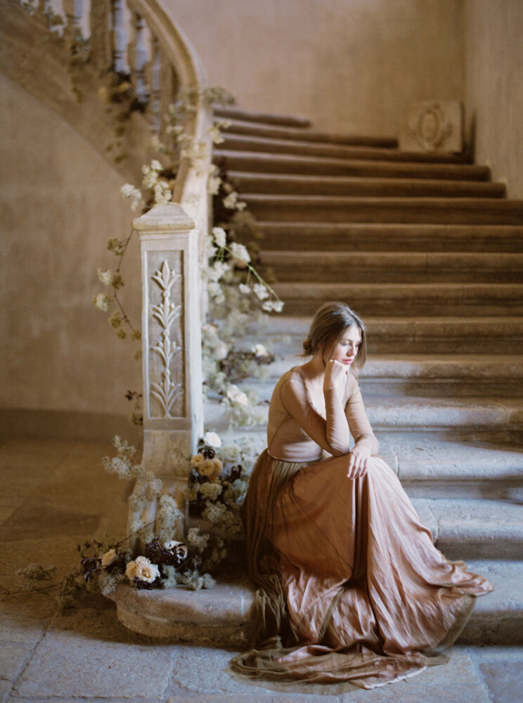 Bride sitting at bottom of stairs in Chateau in Los Angeles