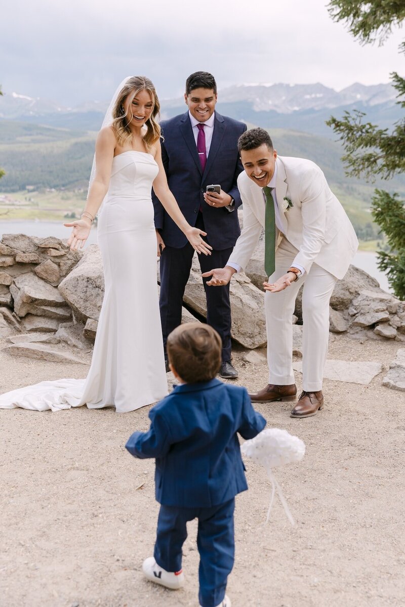 Ring bearer coming up the aisle to a joyful bride and groom at their micro wedding ceremony at Sapphire Point Overlook in Dillon 