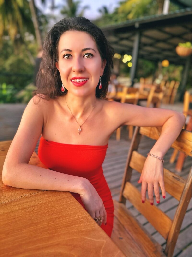 Ana-Maria Georgieva in an orange jumpsuit sitting at a wooden table