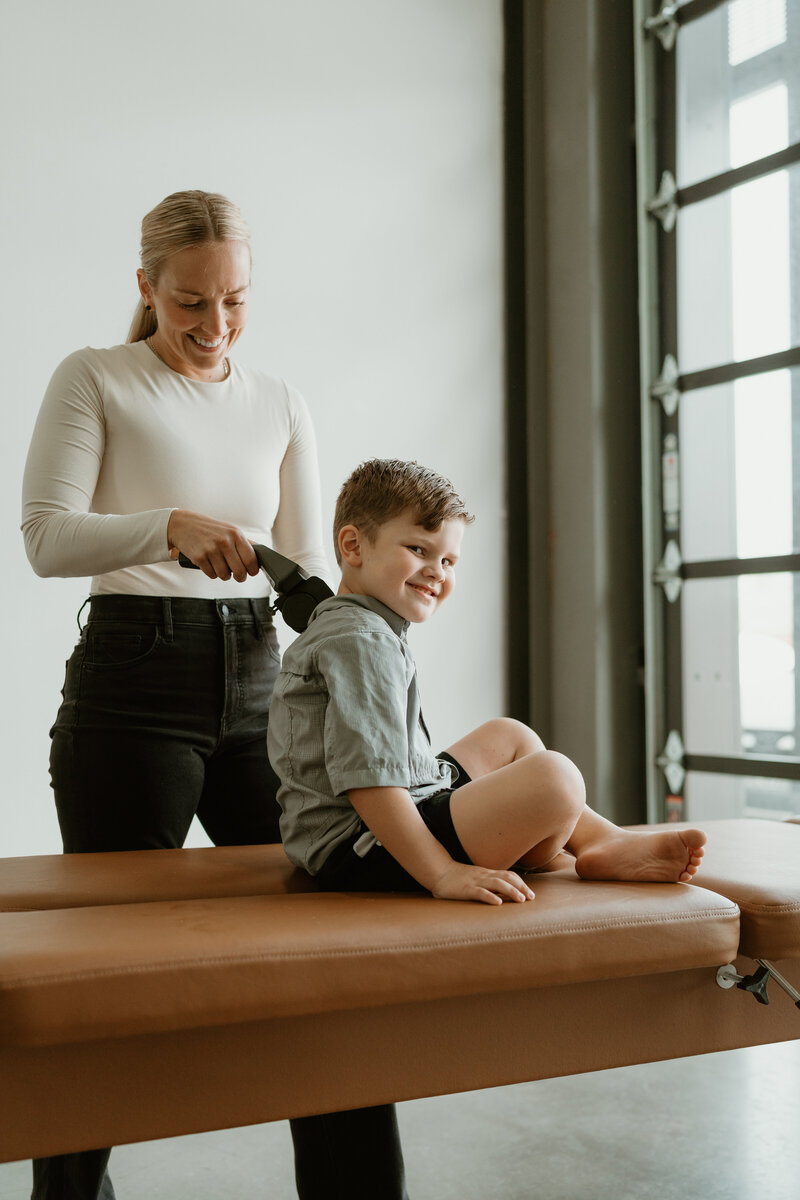 young boy getting adjusted on chiropractic table