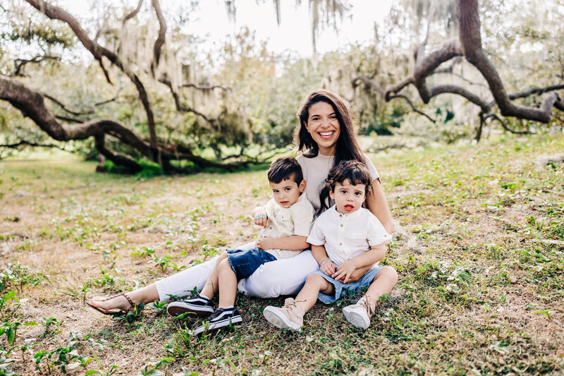 Family playing by the water with sailboats in the background during holiday mini session.