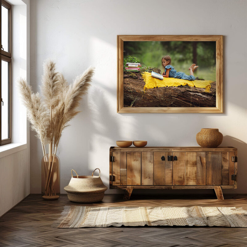 A beautiful hallway with a window to the left. The wall features a large portrait of a little girl laying on a log in the forest. She is on a yellow blanket and reads a book.