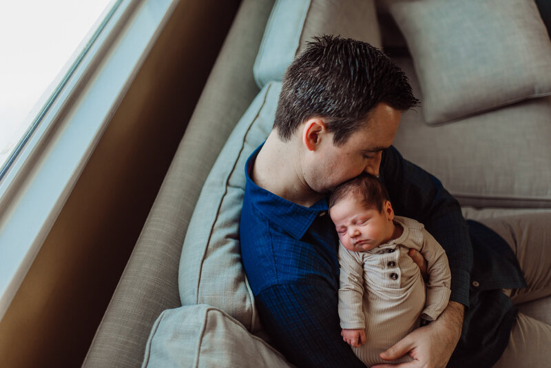 man holding a baby sitting on a couch.