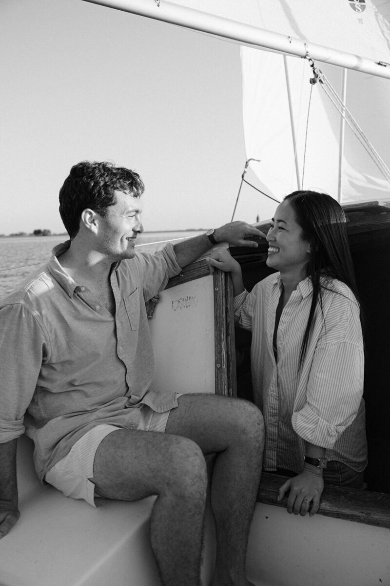 A black and white photo of a Coleen and Casey sitting on a boat, smiling at each other
