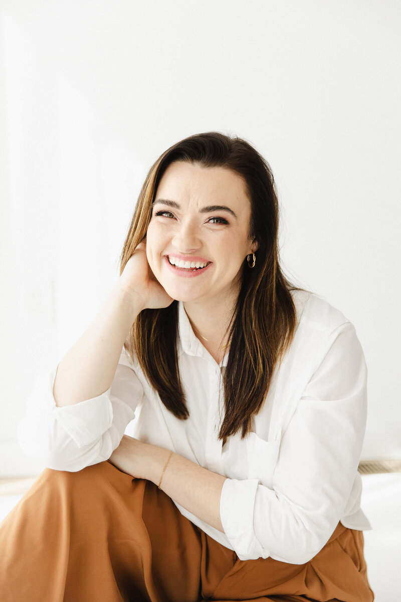 Brunette Woman in a white shirt smiling casually
