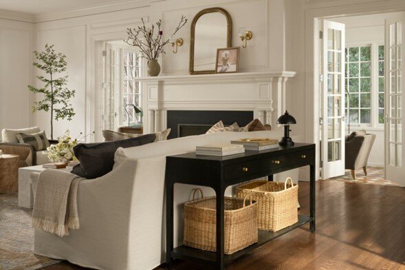 A cozy living room featuring elegant white furniture and a warm fireplace, creating a welcoming atmosphere.