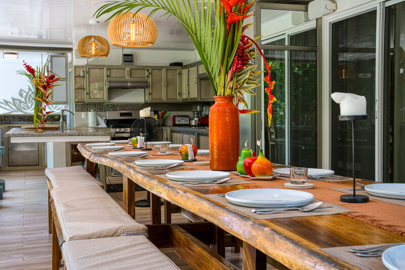 a long table scape with an orange vase and flowers 