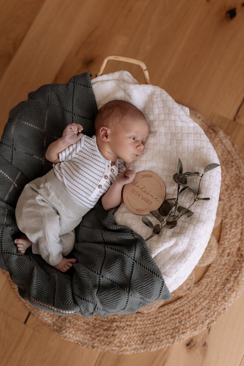 Baby von oben wie es in Korb der mit decken ausgelegt ist liegt