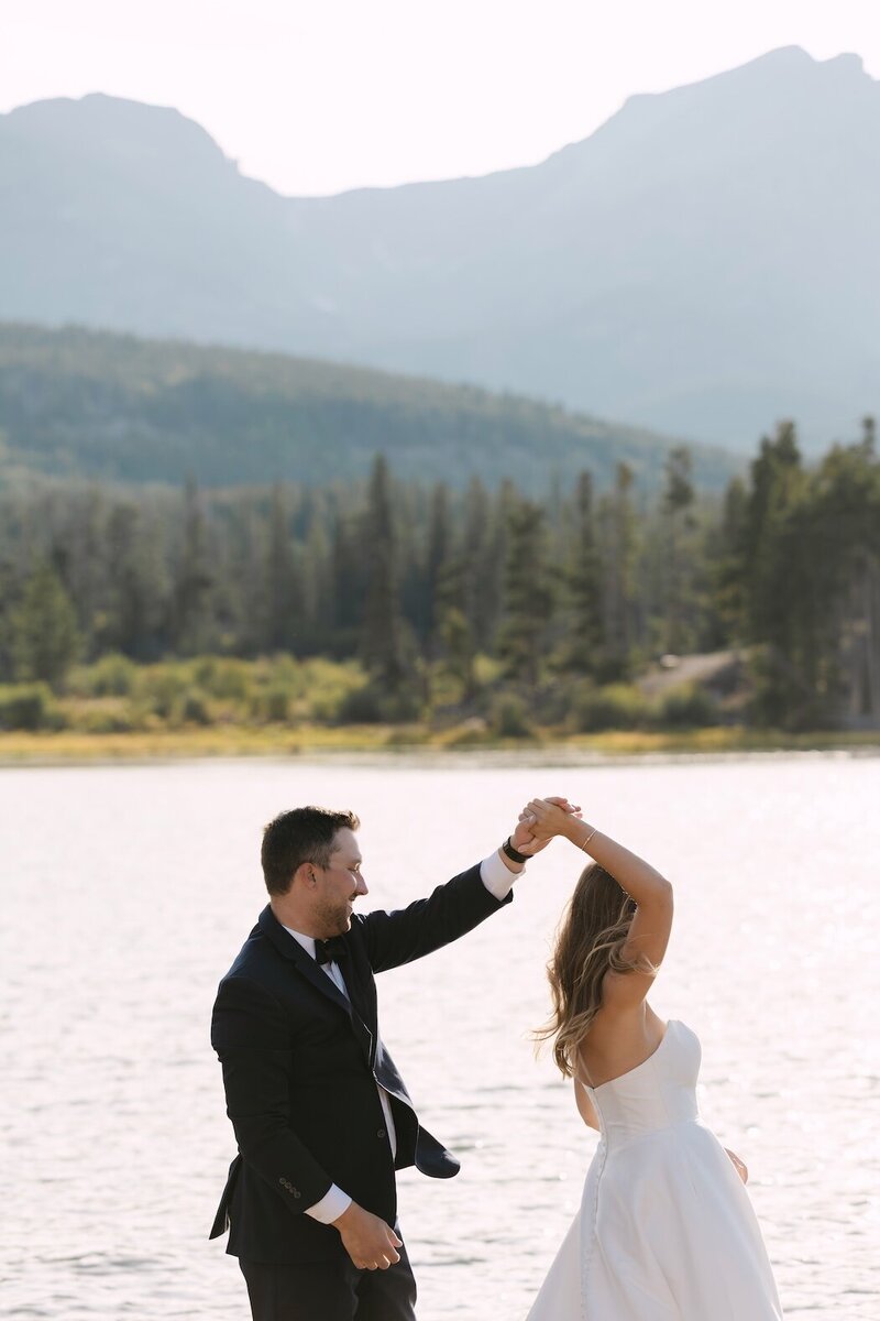 Bride and groom dancing by the water in Rocky Mountain National Park during their Estes Park wedding, captured by Colorado wedding photographer
