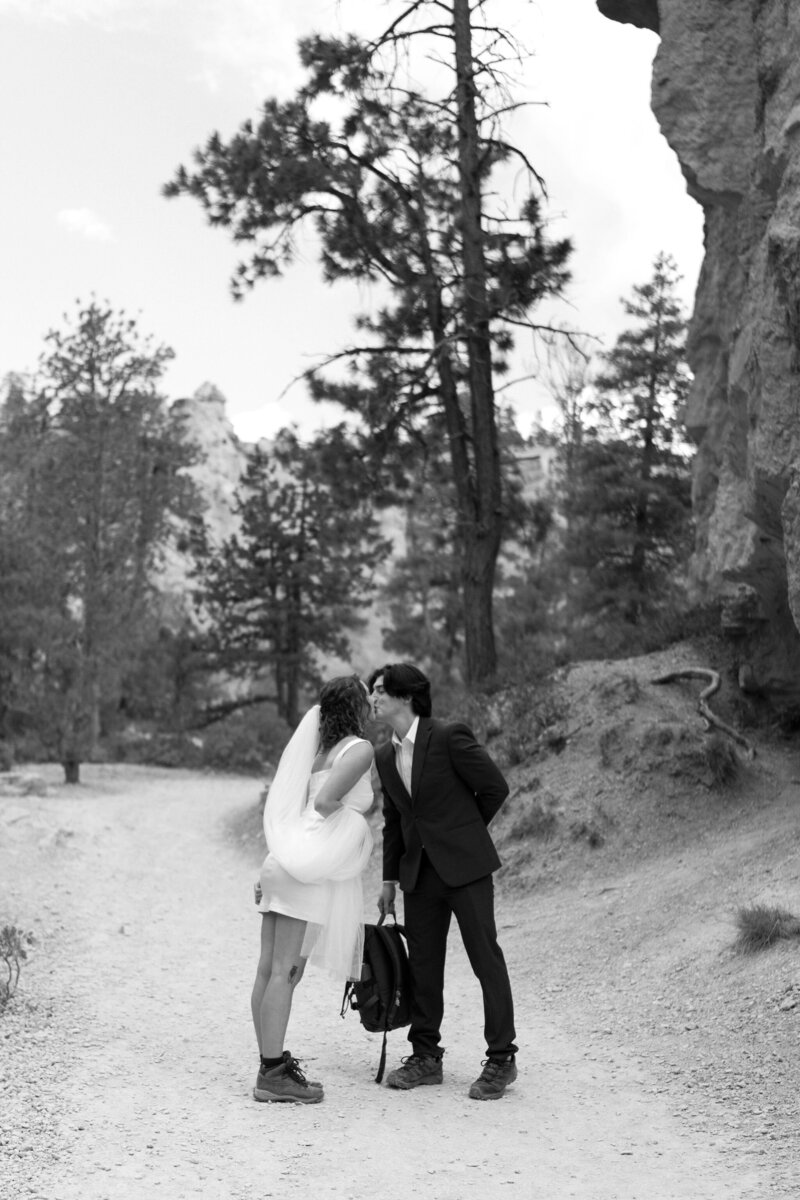 Bride (in short white dress) and Groom (in black suit), wearing hiking boots for their desert elopement