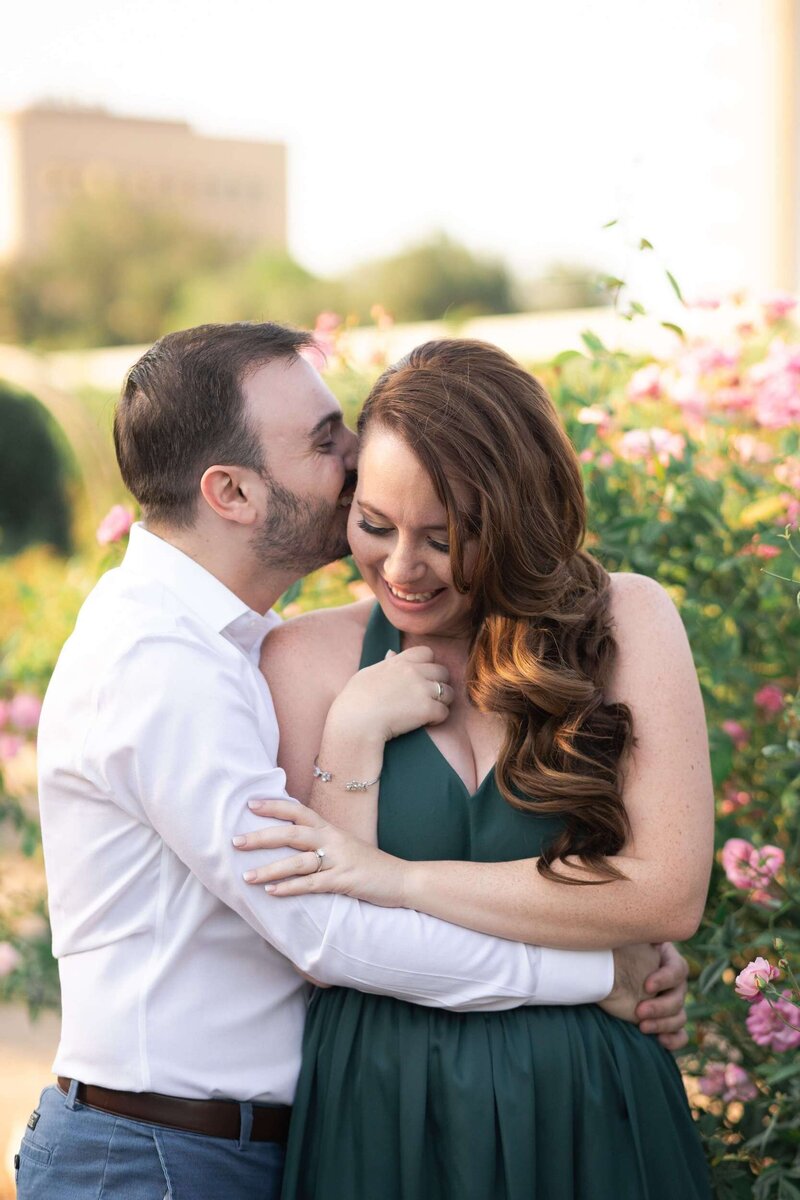 groom to be kisses his fiancé during their engagement session at McGovern Centennial Gardens groom kisses bride to be on a rooftop in downtown Houston by Swish and Click Photography