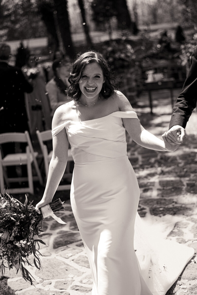 An excited bride walks down the aisle after her spring Washington D.C. wedding ceremony.