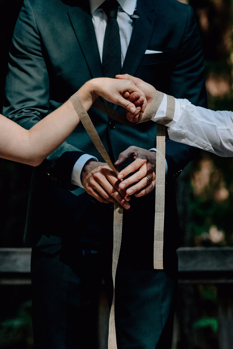 Two hands holding at wedding with man in suit