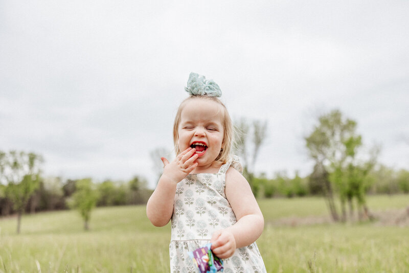 Happy toddler standing in a field eating fruit snacks in De Soto, Missouri. 