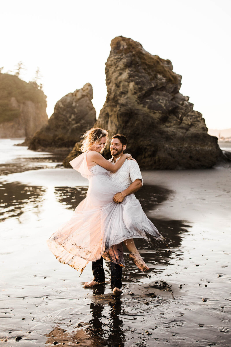 Couple spins on a rocky beach.