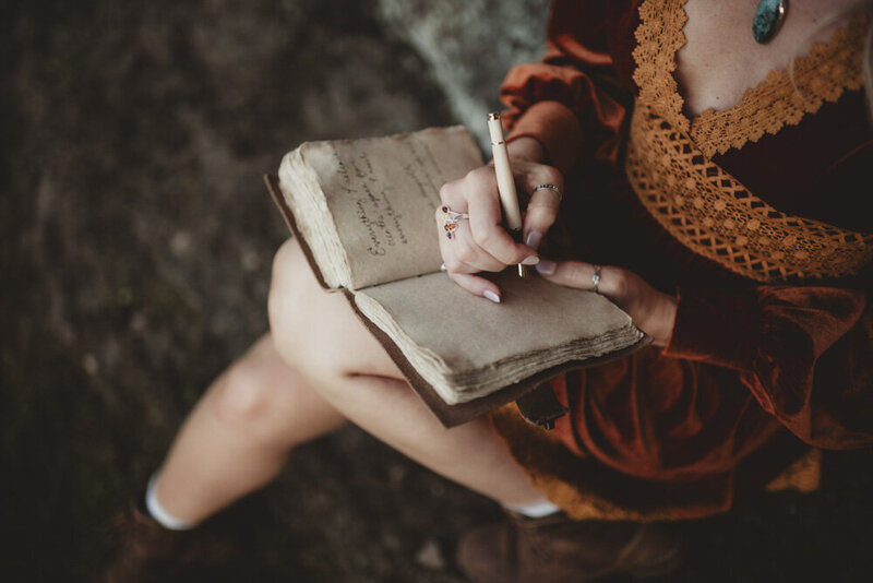 Caroline writing in a weathered journal, capturing thoughts and intentions with peaceful focus.
