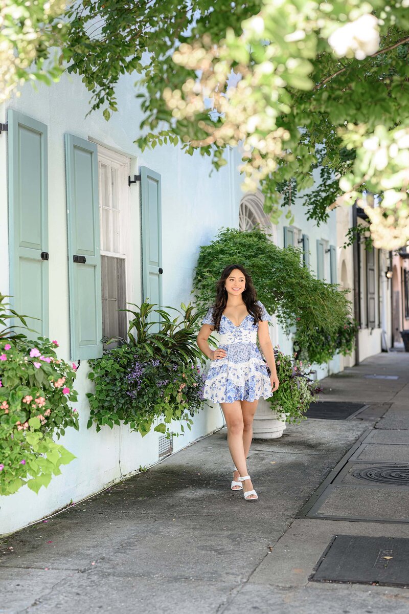 charlotte, nc graduate session with grad wearing a blue romper standing on rainbow row in charleston, sc