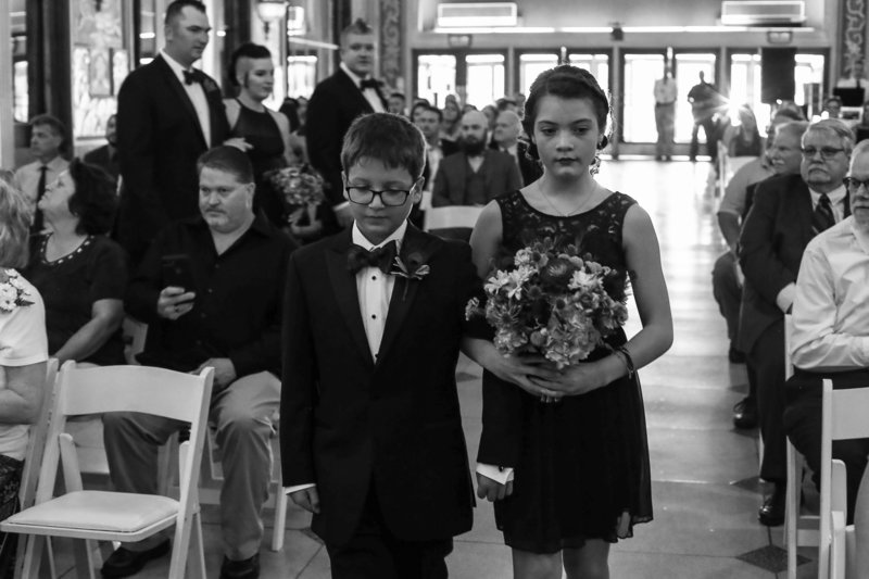 Junior groomsman and junior bridesmaid walk down the aisle together at Warner Theatre wedding