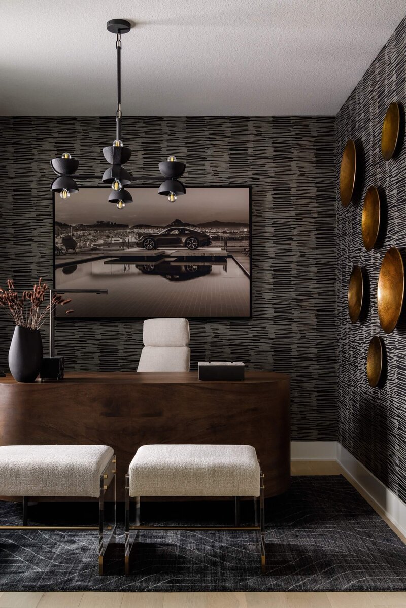 A bold contemporary home office with a dark patterned wallpaper and Porsche artwork with black accents. 