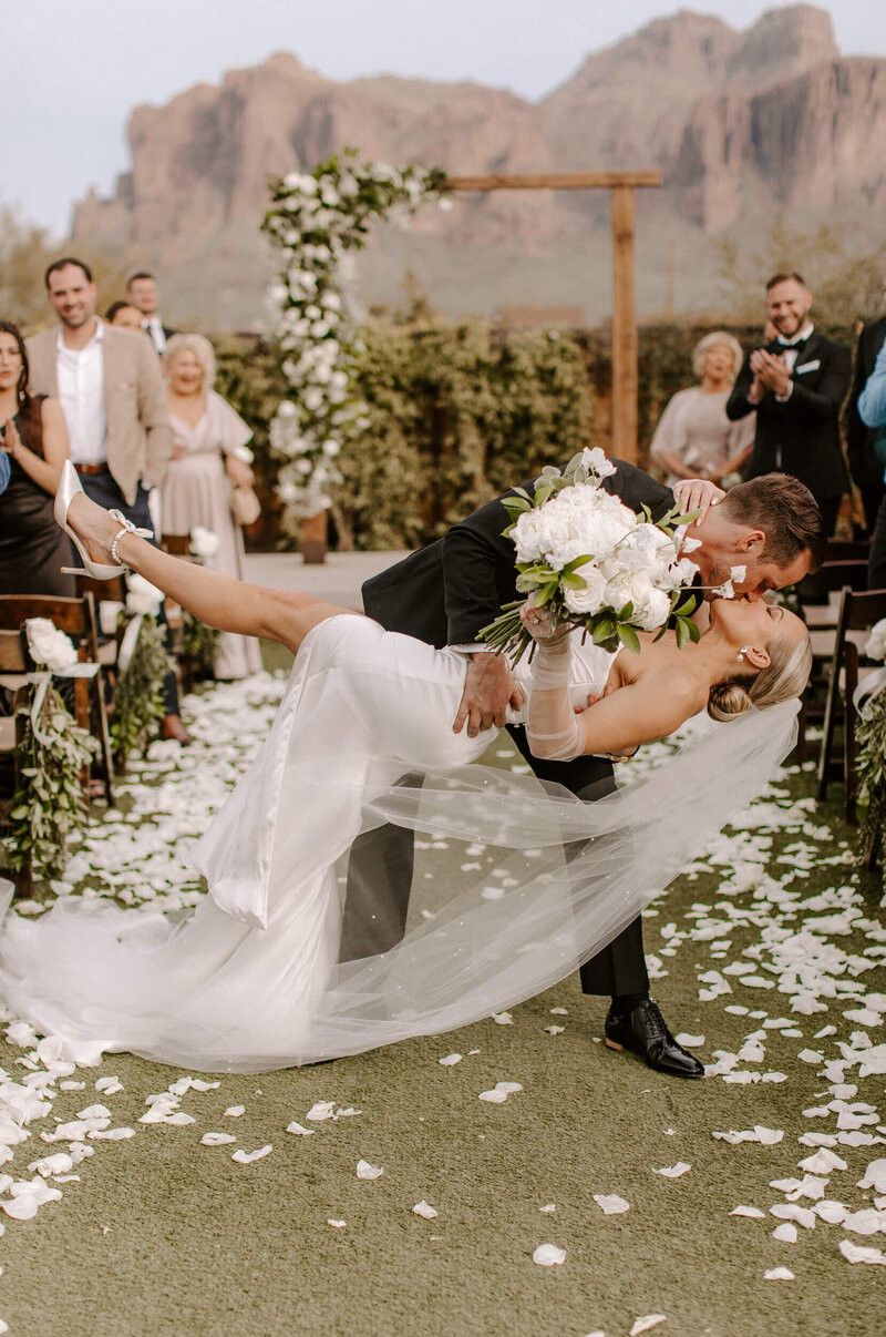 Bride and groom sharing a dip kiss during outdoor Arizona wedding ceremony