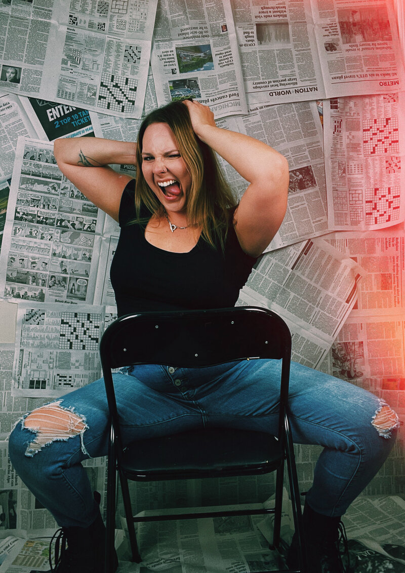 Kristina, a life coach for women, sitting on a chair with hands in her hair, sticking her tongue out at the camera
