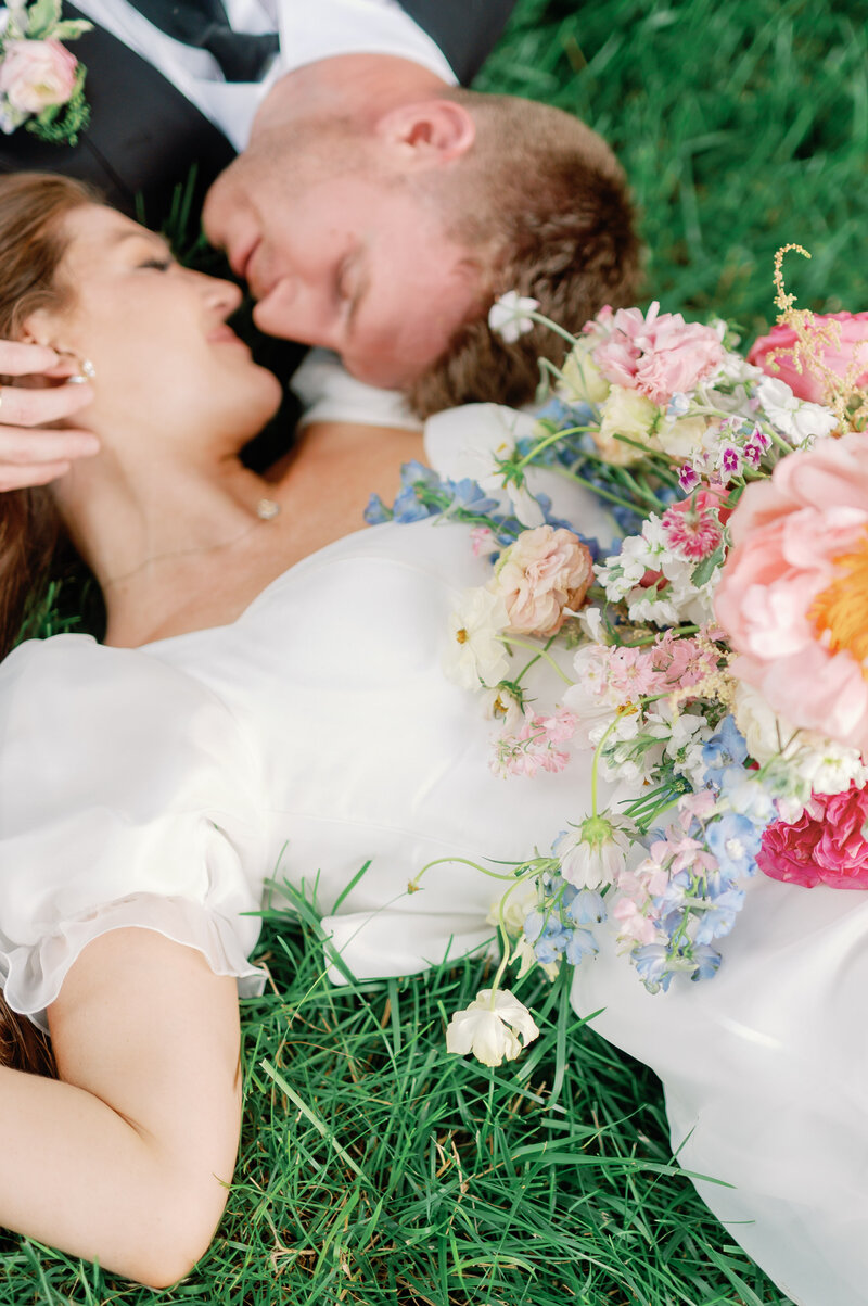a bride and groom laying in the grass together on their wedding day