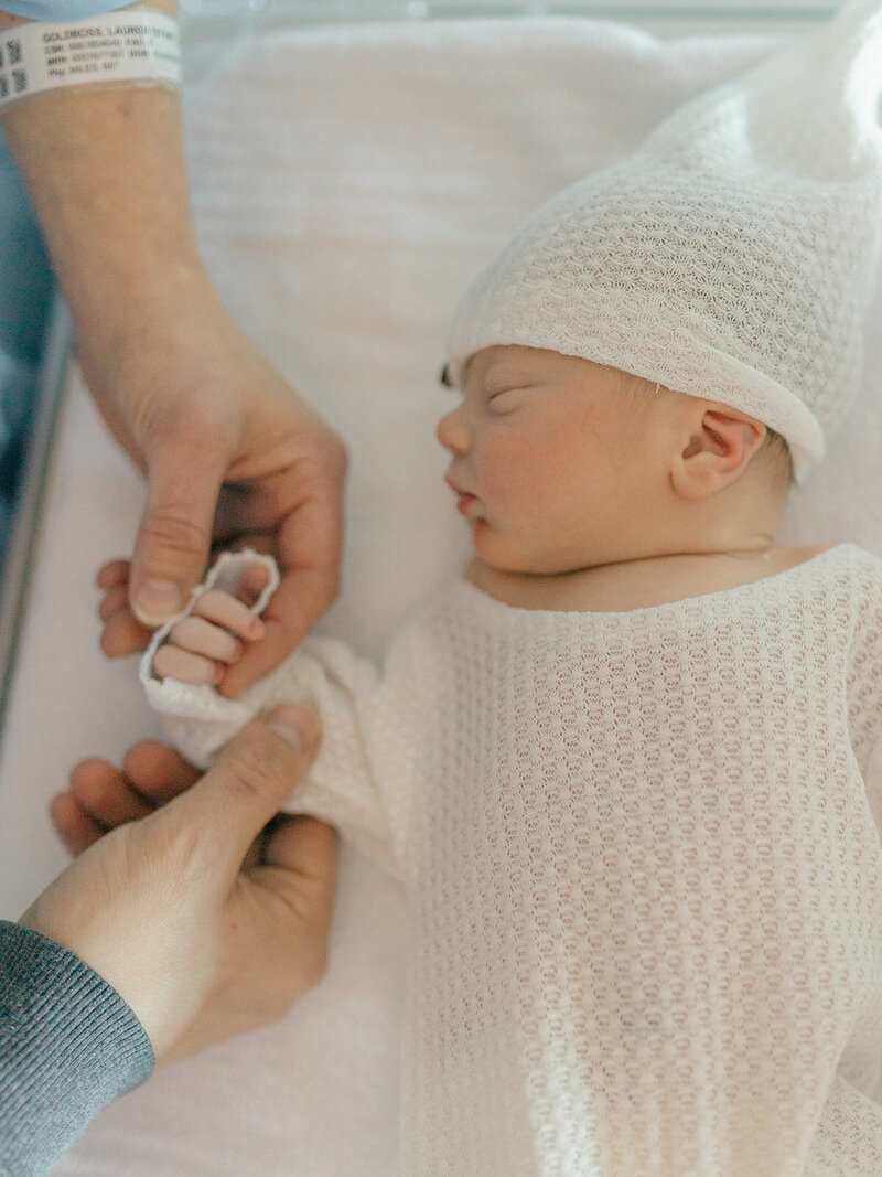 Mom and dad holding newborn baby fingers