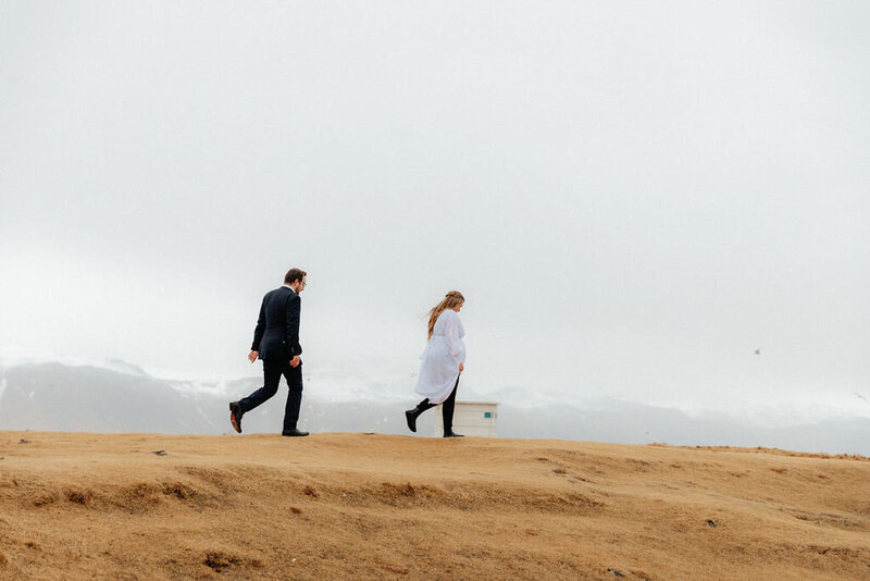 Adventurous bride and groom exploring the cliffs in Arnarstapi Iceland before their wedding ceremony.