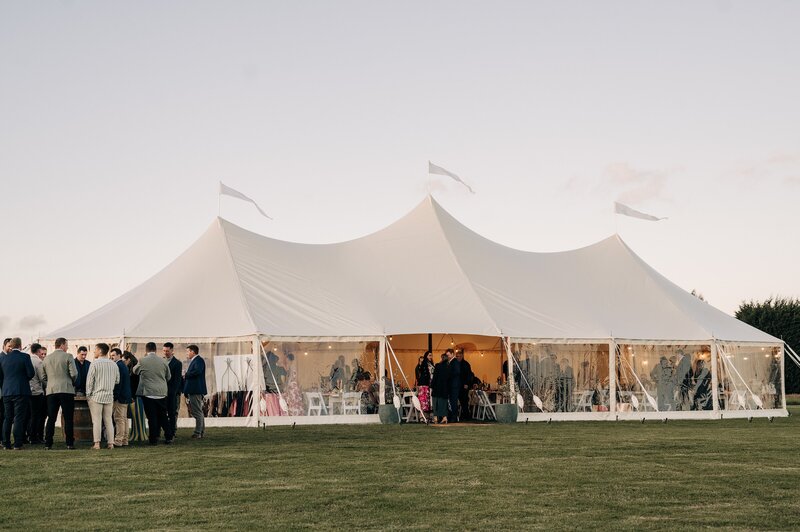 white stretch tents with clear sides and white flags at the farm chapel wedding venue in waimumu gore