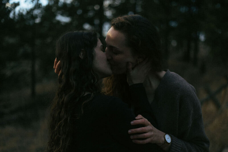 A couple kissing in the woods.