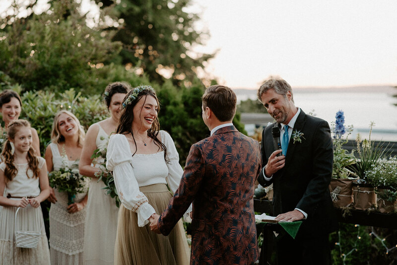 Bride smiles and laughs during outdoor sunset wedding ceremony.