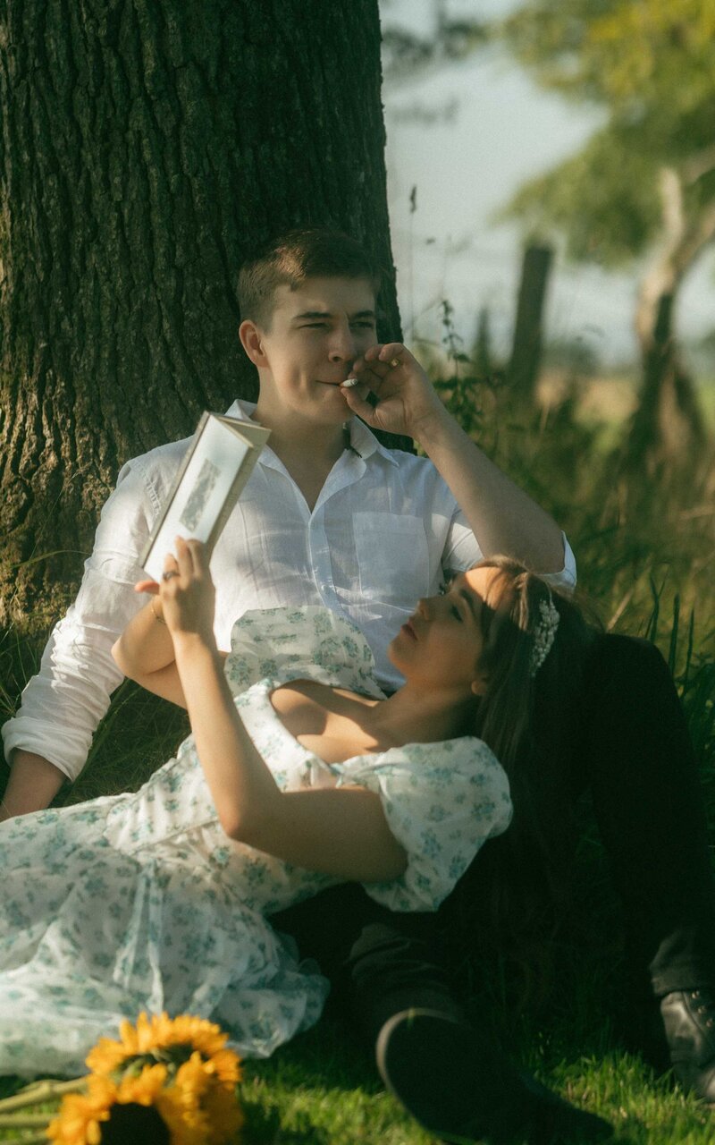 Romantic couple photoshoot capturing a serene moment as they sit under a tree, surrounded by nature's beauty