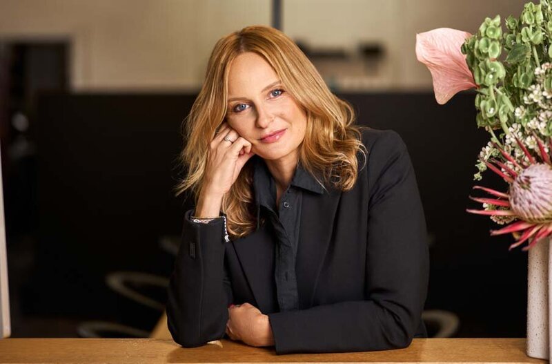 Katy Reeve Professional hair educator leaning on a counter in a salon, surrounded by floral decor.